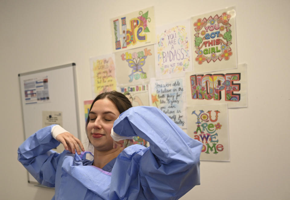 A member of the clinical staff puts on Personal Protective Equipment PPE in the intensive care unit at the Royal Papworth Hospital in Cambridge, England, Tuesday May 5, 2020. (Neil Hall/Pool via AP)