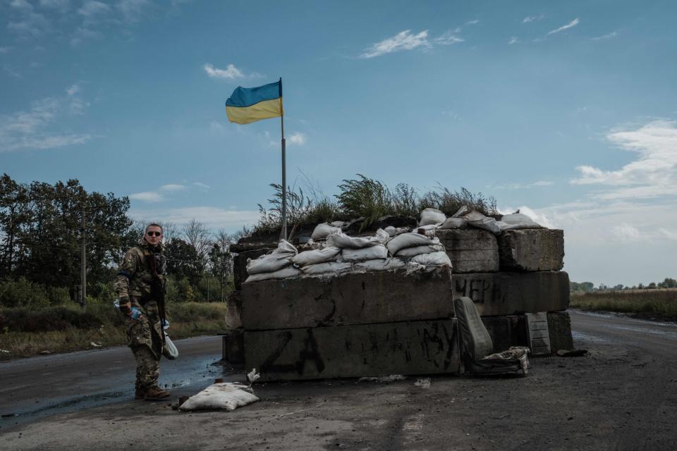 A Ukrainian flag flutters above a retaken checkpoint in Shevchenkove, Kharkiv, on 18 September, 2022. (AFP via Getty Images)