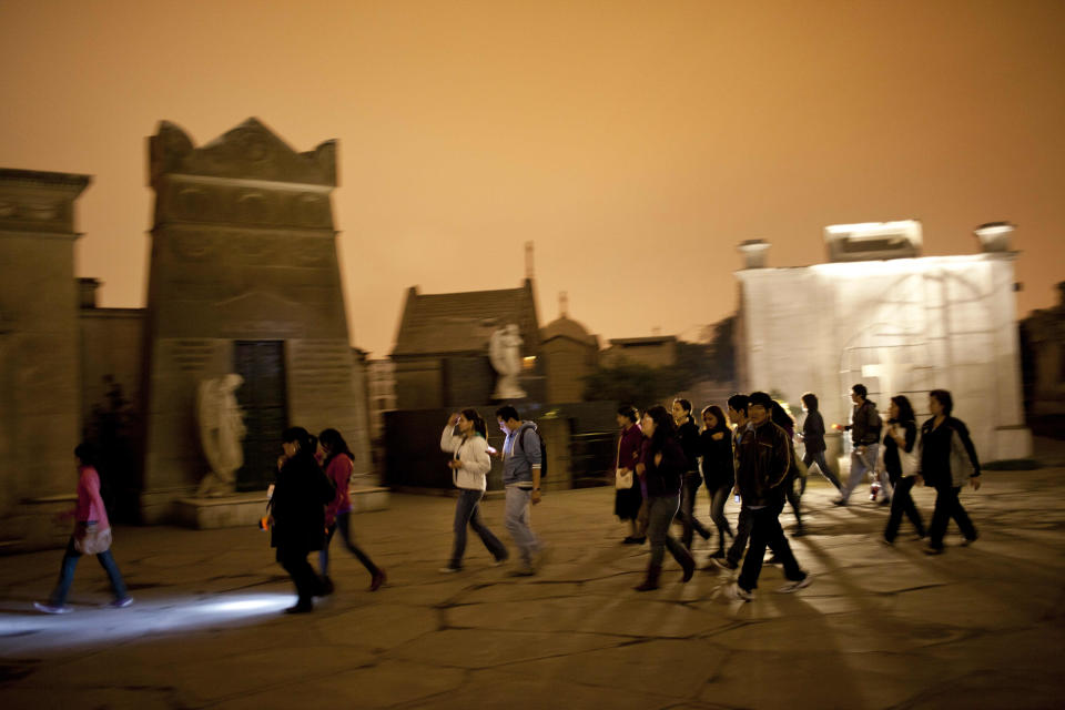 In this Dec. 6, 2012 photo, people take a nighttime guided tour through the Presbitero Matias Maestro cemetery in Lima, Peru. The cemetery, created by one of the last Spanish viceroys, was established the outside the walls of old Lima. (AP Photo/Rodrigo Abd)