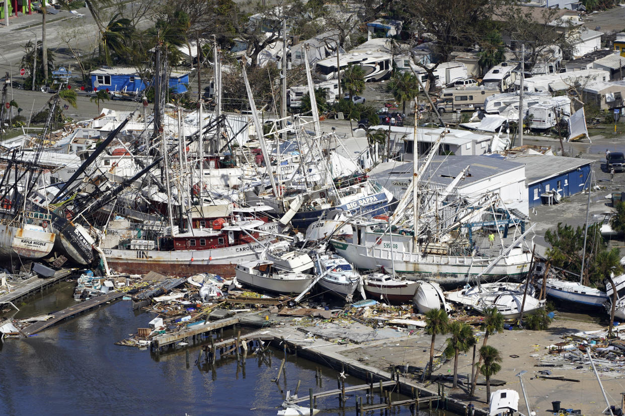 Damaged boats and debris are stacked along the shore.
