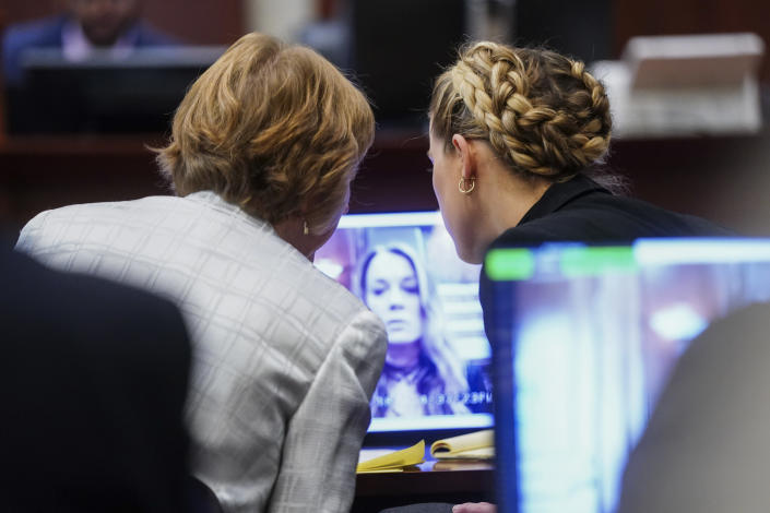 Actress Amber Heard, right, and attorney Elaine Bredehoft, watch video testimony of Heard's former personal assistant Kate James at the Fairfax County Circuit Courthouse in Fairfax, Va., Thursday, April 14, 2022. Actor Johnny Depp sued his ex-wife Amber Heard for libel in Fairfax County Circuit Court after she wrote an op-ed piece in The Washington Post in 2018 referring to herself as a “public figure representing domestic abuse.” (Shawn Thew/Pool Photo via AP)