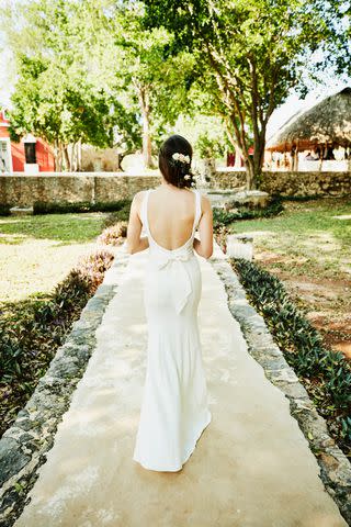 <p>Getty</p> Rear view of bride in wedding gown walking on path at tropical resort before wedding ceremony