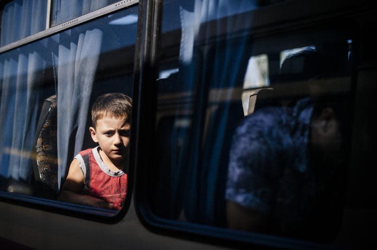 A boy sits in a bus as he waits to leave the besieged rebel stronghold of Donetsk on August 20, 2014 in Donetsk