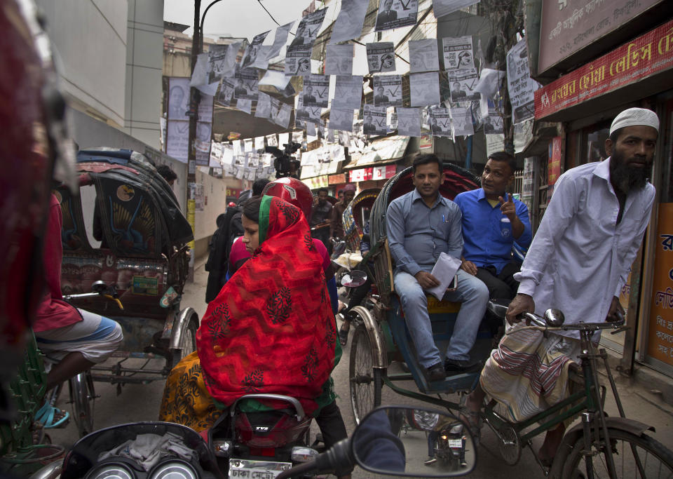 Election posters are seen hanging as Bangladeshi rickshaw pullers transport passengers in Dhaka, Bangladesh, Thursday, Dec. 27, 2018. Bangladesh heads for the 11th National Parliamentary Election on Dec. 30, amid opposition allegations that thousands of its leaders and activists have been arrested to weaken them. But authorities say the arrests are not politically motivated and the opposition is trying to create chaos ahead of elections. (AP Photo/Anupam Nath)