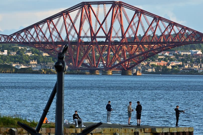 DALGETY BAY, SCOTLAND  - JULY 11: Boys fish from the pier at St David's Harbour as the evening sun catches the Forth Bridge in the background, on July 11, 2023 in Dalgety Bay, Scotland.  (Photo by Ken Jack/Getty Images)