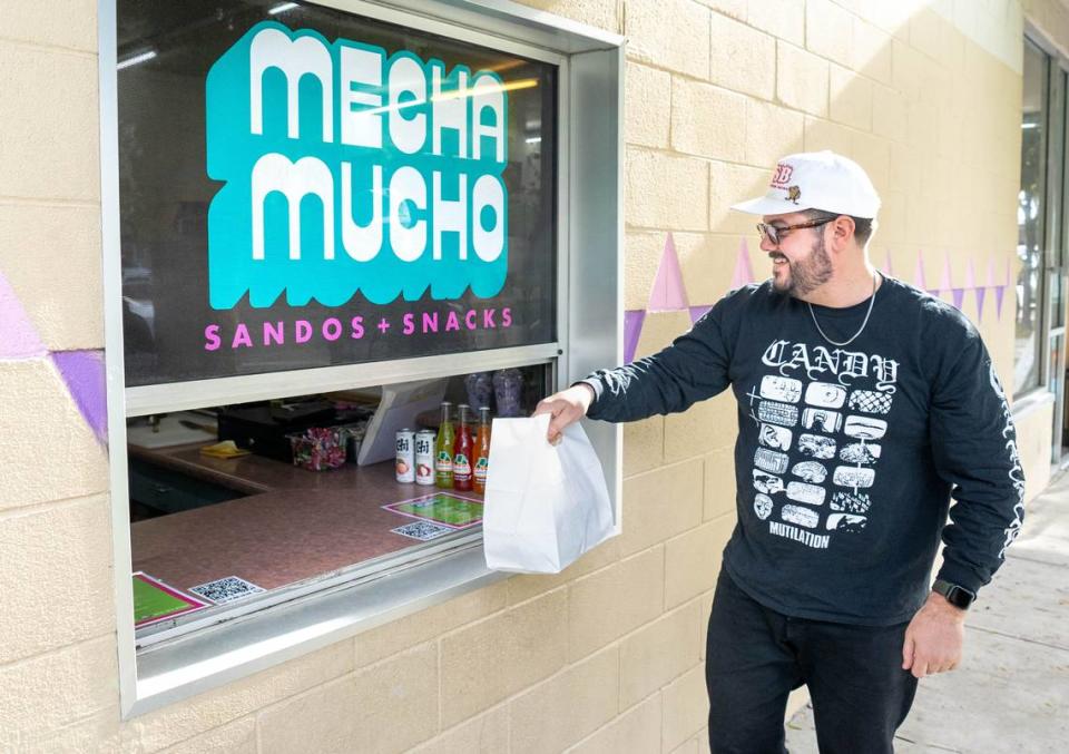 Andrew Calisterio picks up his order from the Mecha Mucho pop-up which operates out of Osaka-Ya’s window in Southside Park on Thursday, Nov. 16, 2023.