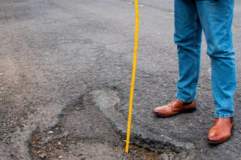 A resident measures the depth of one pot hole in Patching Hall Lane