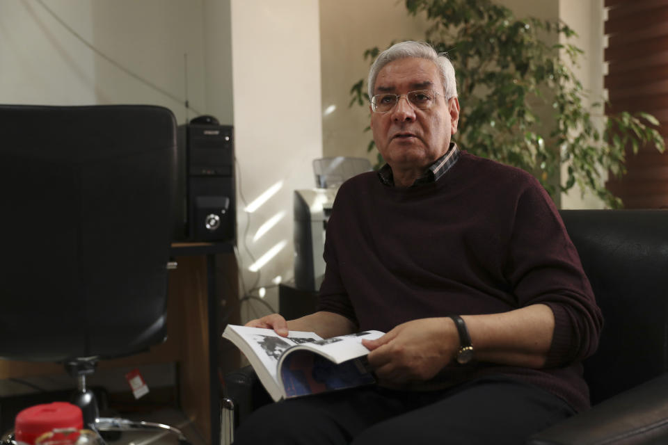 In this Oct. 29, 2019, photo, Ebrahim Asgharzadeh, one of the Iranian student leaders of the 1979 U.S. Embassy takeover, speaks in an interview with The Associated Press as he holds a book about the takeover, in Tehran, Iran. Asgharzadeh says he now regrets the seizure of the diplomatic compound and the 444-day hostage crisis that followed. (AP Photo/Vahid Salemi)