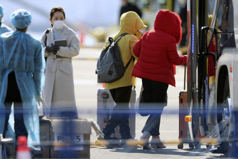 The passengers disembarked from the quarantined Diamond Princess cruise ship walk to buses at a port in Yokohama, near Tokyo, Friday, Feb. 21, 2020. Passengers tested negative for COVID-19 started disembarking since Wednesday. (AP Photo/Eugene Hoshiko)