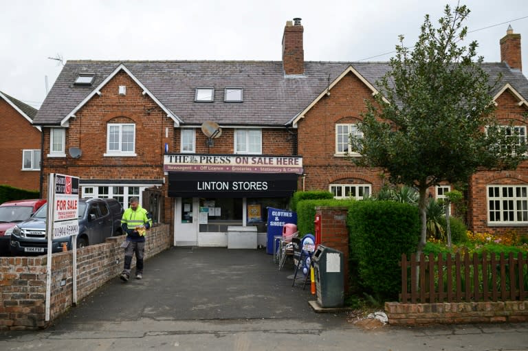 Un hombre sale de la única tienda del pueblo de Linton on Ouse, el 4 de mayo de 2022 al norte de Inglaterra (AFP/Oli Scarff)