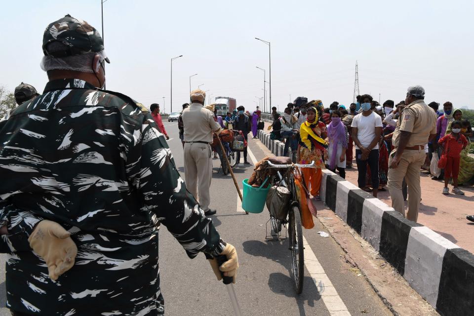 Security personnel stop migrant workers with their families walking back to their native places in Uttar Pradesh and Bihar state as the government eased a nationwide lockdown as a preventive mearure against the COVID-19 coronavirus, in New Delhi on May 14, 2020. (Photo by Prakash SINGH / AFP) (Photo by PRAKASH SINGH/AFP via Getty Images)