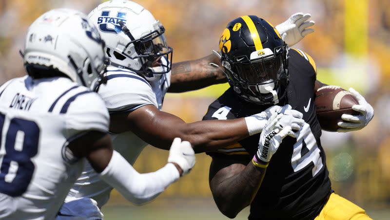 Iowa running back Leshon Williams (4) tries to break a tackle by Utah State safety Anthony Switzer during the first half of an NCAA college football game, Saturday, Sept. 2, 2023, in Iowa City, Iowa. 