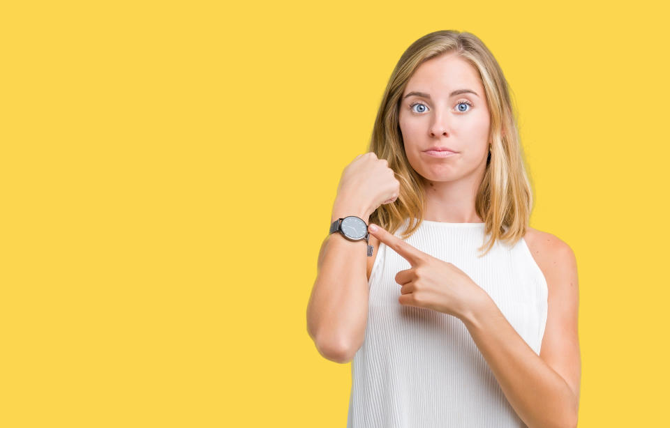 Beautiful young elegant woman over isolated background In hurry pointing to watch time, impatience, upset and angry for deadline delay