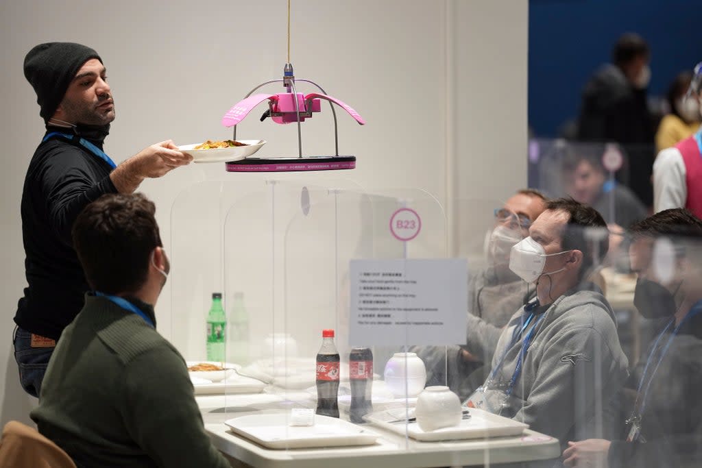 Food is delivered using an automated system to a table at the media dining room during the 2022 Winter Olympics (AP)