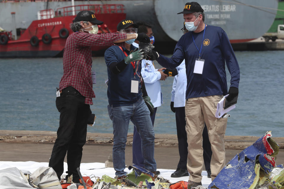 Members of the U.S. National Transportation Safety Board (NTSB) investigators team inspect debris found in the waters around the location where a Sriwijaya Air passenger jet crashed, at the search and rescue command center at Tanjung Priok Port in Jakarta, Indonesia, Saturday, Jan. 16, 2021. The NTSB joined the crash investigation with Indonesian National Transportation Safety Committee. (AP Photo/Achmad Ibrahim)