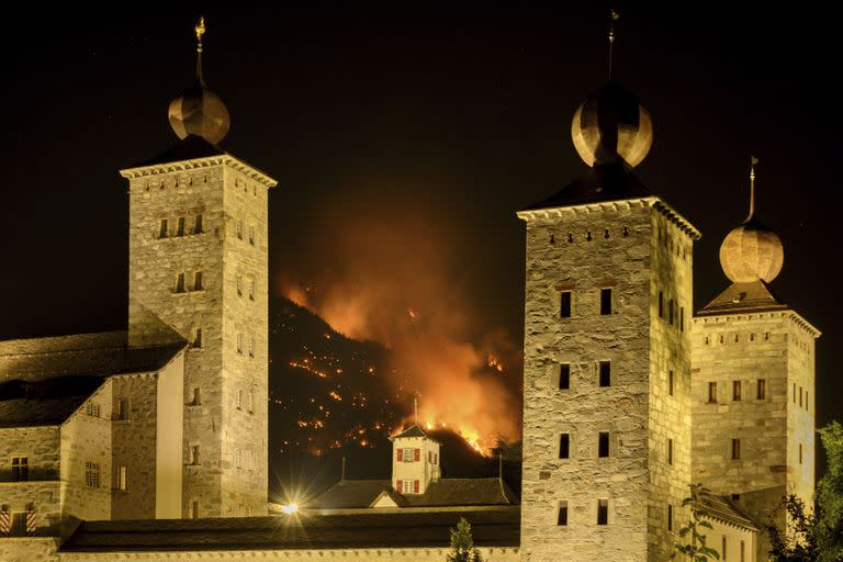 Se observa humo y llamas provenientes de un bosque en llamas detrás del palacio de Stockalper, sobre las comunas de Bitsch y Ried-Moerel, en Bitsch, Suiza, el lunes 17 de julio de 2023.