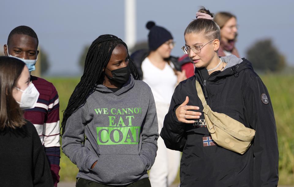 Climate activists Vanessa Nakate from Uganda and Leonie Bremer of the German Fridays for Future movement, right, visit the Garzweiler open-cast coal mine in Luetzerath, western Germany, Saturday, Oct. 9, 2021. Garzweiler, operated by utility giant RWE, has become a focus of protests by people who want Germany to stop extracting and burning coal as soon as possible. The village of Luetzerath, now almost entirely abandoned as the mine draws ever closer, will be the latest village to disappear as coal mining at the Garzweiler mine expands. (AP Photo/Martin Meissner)