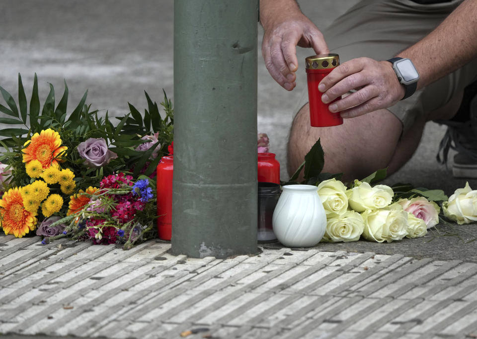 A person puts a candle on the floor between flowers and candles at the Kaiser Wilhelm Memorial Church in Berlin, Germany, Thursday, June 9, 2022. On Wednesday June 8, a 29-year-old man drove his car into a group of students killing their teacher and crash into a store. (AP Photo/Michael Sohn)