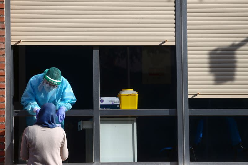 A health worker gives the results of a coronavirus disease (COVID-19) antigen test to a woman, in Madrid