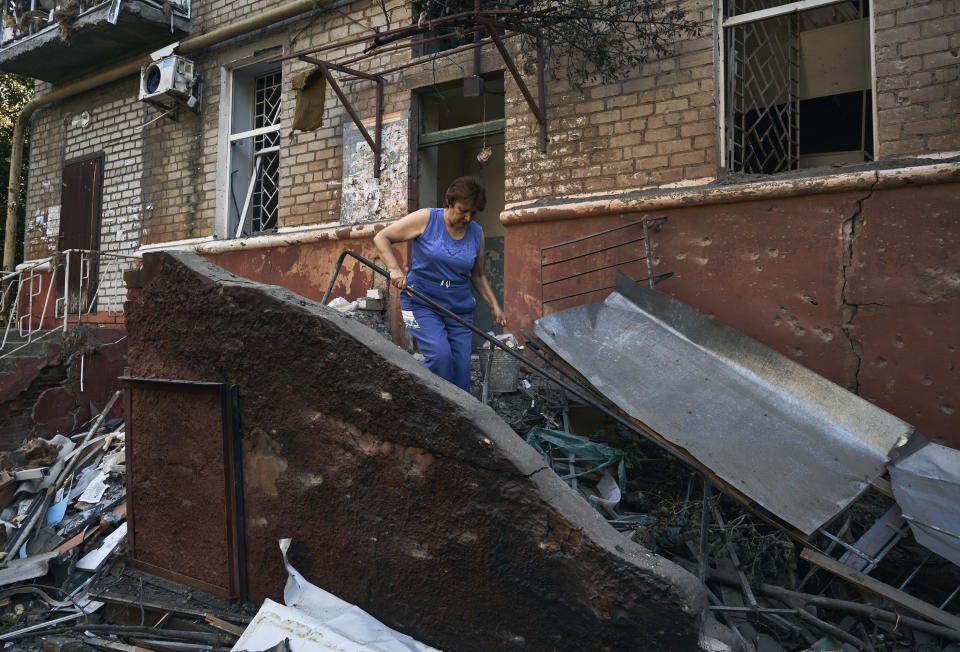 A woman cleans up debris in front of a residential building that was damaged after a Russian rocket attack in Kramatorsk, eastern Ukraine, Wednesday, Aug. 31, 2022. (AP Photo/Kostiantyn Liberov)