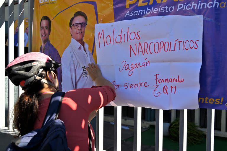 Un ciclista cuelga una pancarta contra la narcoviolencia en la barandilla del complejo deportivo donde fue asesinado en la víspera el candidato presidencial ecuatoriano Fernando Villavicencio, en Quito, el 10 de agosto de 2023. . (Foto de Rodrigo BUENDIA / AFP)