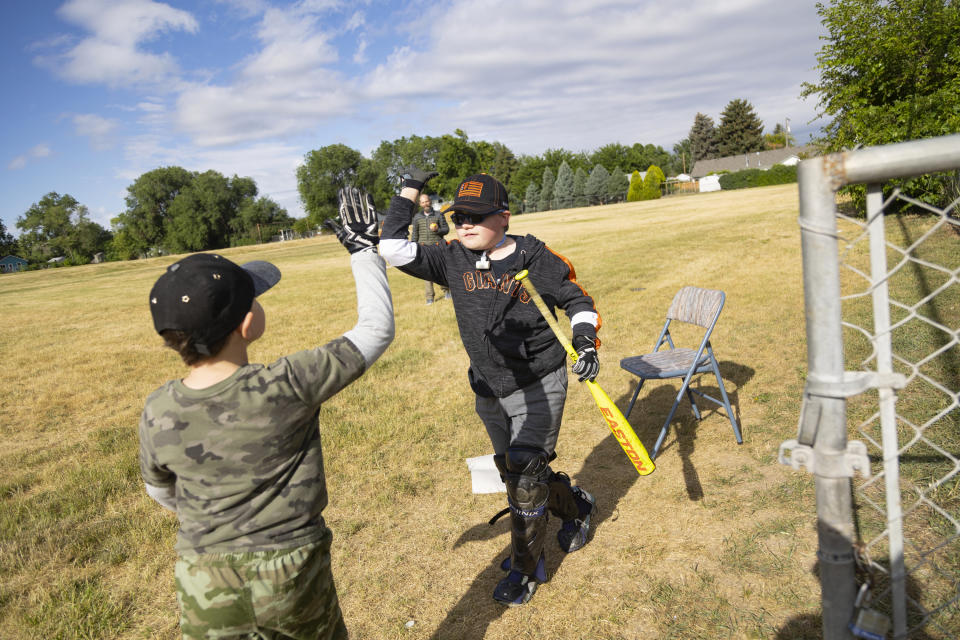 Brady Hill high fives his brother Monte, 8, during a baseball game at their home in Meridian, Idaho, June 19, 2023. Brady survived a rare brain cancer as a baby, but requires round the clock care. Families of severely disabled children across the country are worried about the future of crucial Medicaid payments they started receiving to provide care during the COVID-19 pandemic. (AP Photo/Kyle Green)