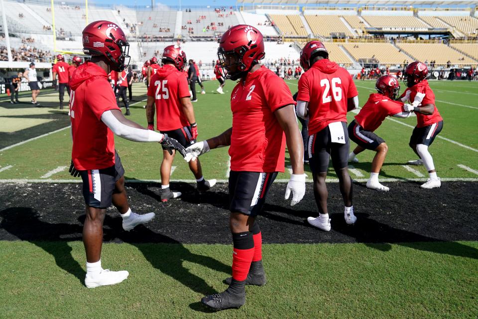 Cincinnati Bearcats running back Ryan Montgomery (22), left, and Cincinnati Bearcats running back Corey Kiner (2), right, shake hands during warm ups before the first quarter of a college football game against the UCF Knights, Saturday, Oct. 29, 2022, at FBC Mortgage Stadium in Orlando, Fla. Both are battling for carries again for the 2023 UC Bearcats.