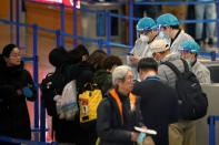 Medical officials are seen as passengers leave at the Pudong International Airport in Shanghai