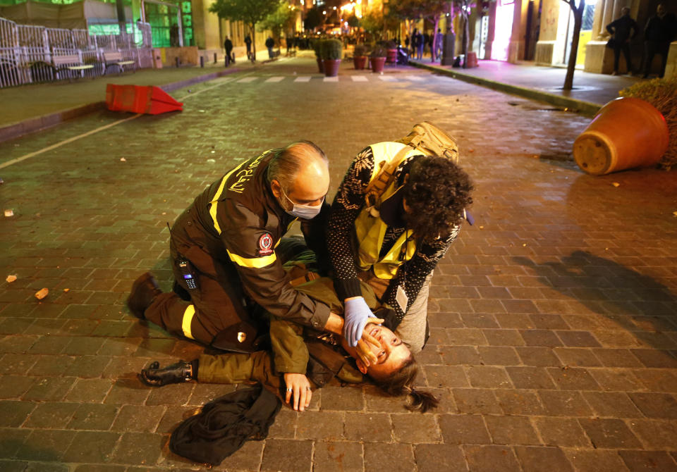 Civil defense workers treat an injured protester injured during a protest where anti-government protesters try to enter the parliament square in downtown Beirut, Lebanon, Saturday, Dec. 14, 2019. The recent clashes marked some of the worst in the capital since demonstrations began two months ago. The rise in tensions comes as politicians have failed to agree on forming a new government. (AP Photo/Hussein Malla)