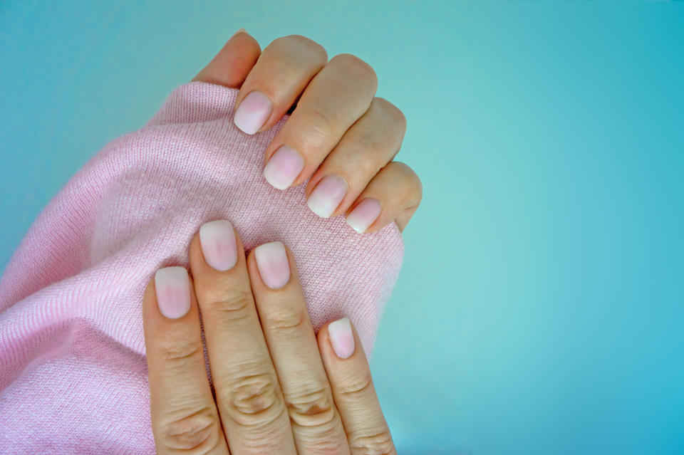 Beautiful gradient manicure. White and pink ombre on both hands. Light blue background.