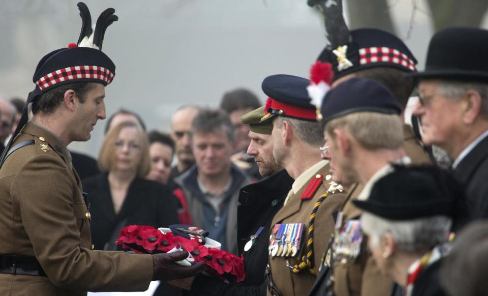 A soldier of the Scottish Division Honor Guard, left, hands over the personal effects of British World War One soldier William McAleer to his grand-nephew Stephen McLeod, center, during a reburial service at the Loos British World War One cemetery in Loos-en-Gohelle, France on Friday, March 14, 2014. Private William McAleer, of the 7th Battalion, Royal Scots Fusiliers, was killed in action on Sept. 26, 1915 during the Battle of Loos. His body was found and identified in 2010 during routine construction in the area and is being reburied with full military honors along with 19 unknown soldiers. (AP Photo/Virginia Mayo)