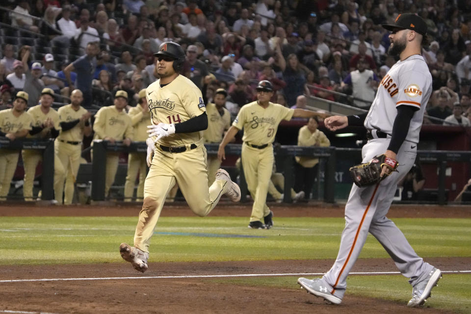 Arizona Diamondbacks' Gabriel Moreno (14) scores a run on a passed ball thrown by San Francisco Giants pitcher Jakob Junis, right, in the sixth inning during a baseball game, Friday, May 12, 2023, in Phoenix. (AP Photo/Rick Scuteri)