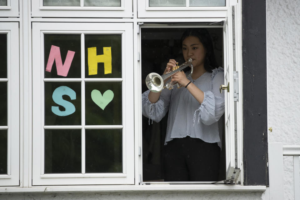 National Youth Orchestra of Great Britain trumpet player Tian Hsu, 16, takes part in a socially distanced orchestra performance of Beethoven's "Ode to Joy" from a window of her home in south west London, during the lockdown to prevent the spread of coronavirus, Friday, April 17, 2020. The members of the National Youth Orchestra, took part in the coordinated Ode to Joy-a-thon on Friday, each giving their own 40 second performance, with photos or videos taken by their families to share on social media. They dedicated the performance to the National Health Service staff, key workers, and people who feel isolated in their homes during the lockdown. (AP Photo/Matt Dunham)