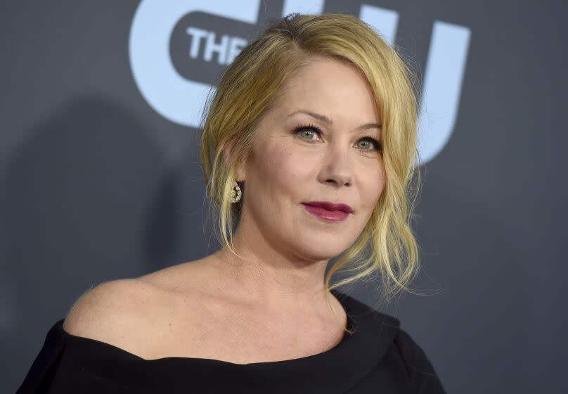 A woman with blond hair posing in dark pink lipstick and a black dress