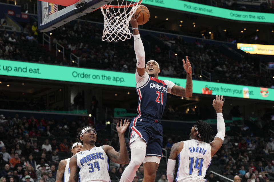 Washington Wizards center Daniel Gafford (21) scores as Orlando Magic center Wendell Carter Jr. (34) and guard Gary Harris (14) defend during the first half of an NBA basketball game, Saturday, Jan. 21, 2023, in Washington. (AP Photo/Jess Rapfogel)