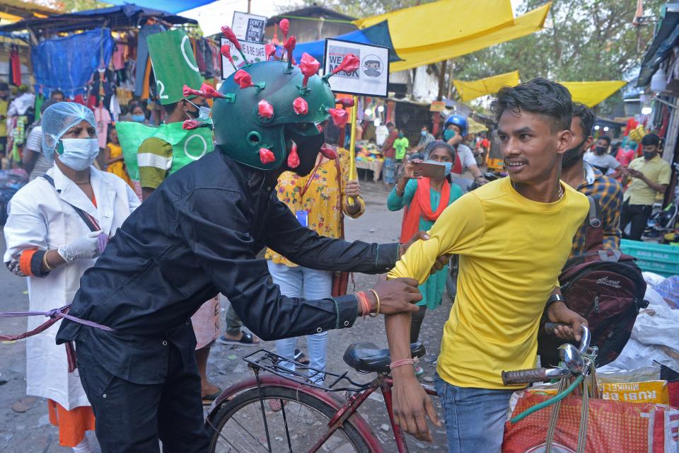 TOPSHOT - A man from a Non-governmental organization (NGO) wearing an outfit resembling the Covid-19 coronavirus moves around a marketplace urging people to follow the safety protocols during an awareness drive held in Siliguri on April 25, 2021. (Photo by DIPTENDU DUTTA / AFP) (Photo by DIPTENDU DUTTA/AFP via Getty Images)