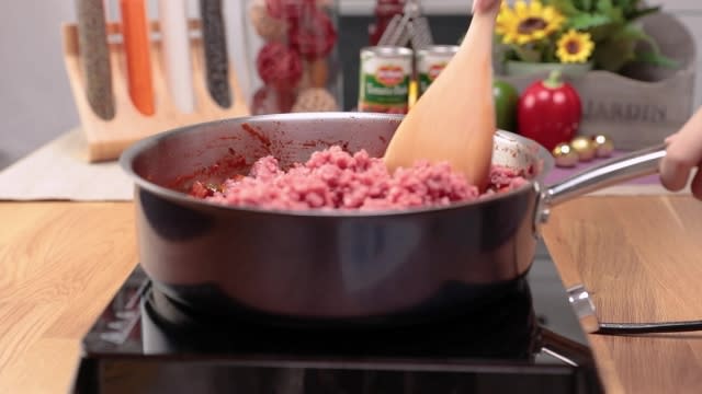 Frying minced beef in a frying pan with a wooden spatula