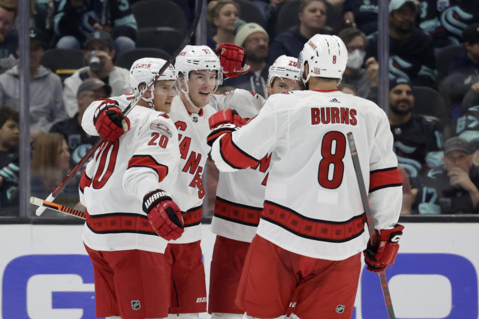 Carolina Hurricanes center Sebastian Aho (20) celebrates his goal against the Seattle Kraken with right wing Andrei Svechnikov (37) and defenseman Brent Burns (8) during the second period of an NHL hockey game, Monday, Oct. 17, 2022, in Seattle. (AP Photo/John Froschauer)