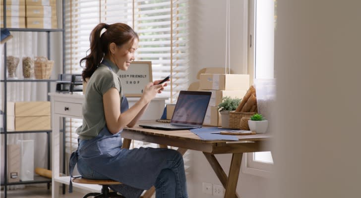 A woman happily opens a certificate deposit account on her phone with a 5% annual percentage yield. 