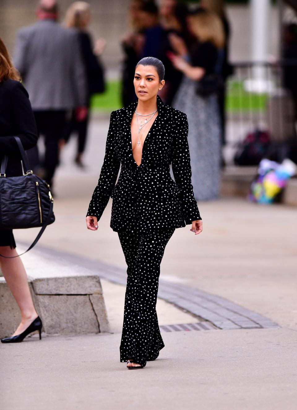 Kourtney in a black suit with silver sparkles throughout and no shirt underneath.