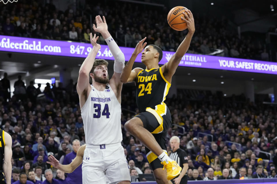 Iowa forward Kris Murray, right, drives to the basket against Northwestern center Matthew Nicholson during the first half of an NCAA college basketball game in Evanston, Ill., Sunday, Feb. 19, 2023. (AP Photo/Nam Y. Huh)