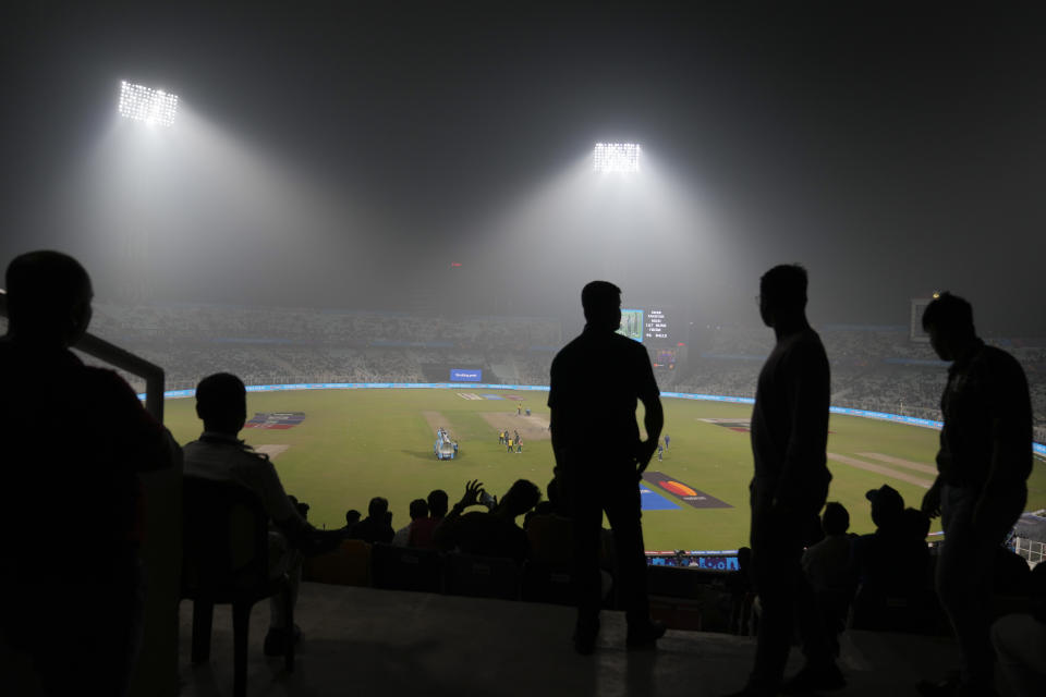 Spectators are silhouetted against lights as smog engulfs the stadium during the ICC Men's Cricket World Cup match between Pakistan and England in Kolkata, India, Saturday, Nov. 11, 2023. (AP Photo/Altaf Qadri)