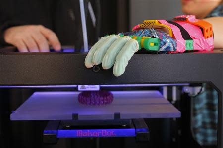 Twelve-year-old Leon McCarthy rests his prosthetic hand on a MarkerBot Replicator 2 Desktop 3D Printer at the new MakerBot store in Boston, Massachusetts November 21, 2013. REUTERS/Brian Snyder