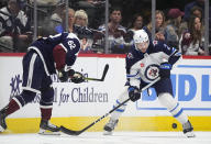 Winnipeg Jets defenseman Dylan DeMelo, right, struggles to collect the puck as Colorado Avalanche left wing Artturi Lehkonen, left, defends in the second period of an NHL hockey game Saturday, April 13, 2024, in Denver. (AP Photo/David Zalubowski)