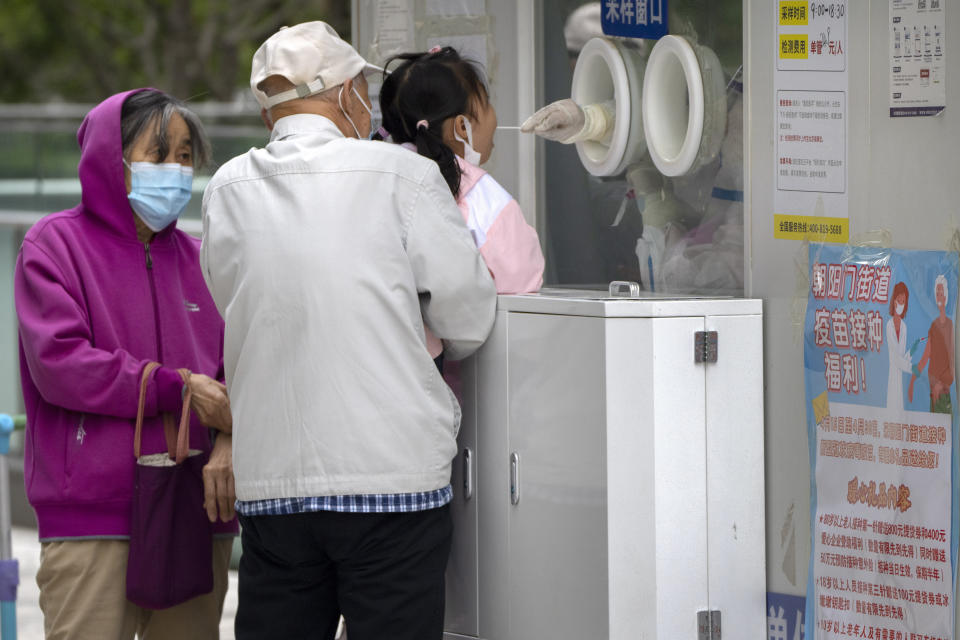 A child receives a throat swab for a COVID-19 test at a testing site in Beijing, Thursday, April 28, 2022. Beijing shifted more classes online Thursday in a further tightening of COVID-19 restrictions, as China's capital seeks to prevent a wider outbreak. (AP Photo/Mark Schiefelbein)