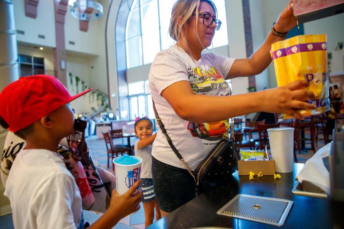 Cristal Yanez of Cathedral City adds butter to the popcorn as her son Lennon Valdivia, 6, and daughter Angelina Valdivia, 5, look on before seeing &quot;Minions: The Rise of Gru&quot; at Mary Pickford is D’Place in Cathedral City, Calif., on June 30, 2022.