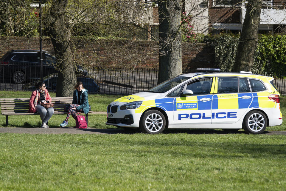 Police ask two women to move on in Primrose Hill, London, Sunday April 5, 2020, as the UK continues in lockdown to help curb the spread of the coronavirus. The new coronavirus causes mild or moderate symptoms for most people, but for some, especially older adults and people with existing health problems, it can cause more severe illness or death.(Aaron Chown/PA via AP)