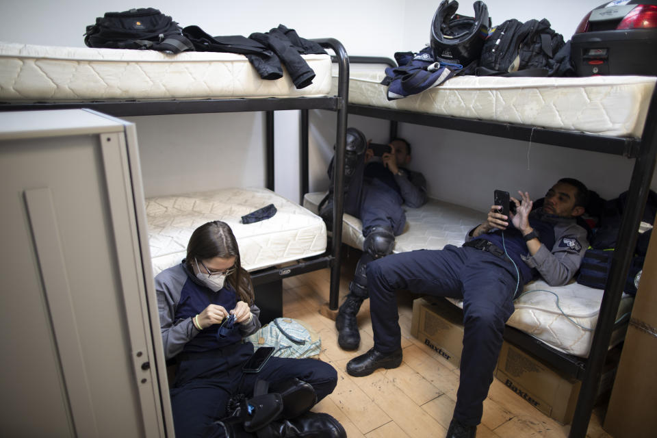 Wearing masks as a precaution against the new coronavirus, Angels of the Road volunteer paramedics Laura Lara, from left, Alexander Barreto and Bran Cabello, relax in the only room they have at their operations base in Caracas, Venezuela, Monday, Feb. 8, 2021. Their operations base is located in a rented office space in a national newspaper building that no longer prints a paper edition. (AP Photo/Ariana Cubillos)