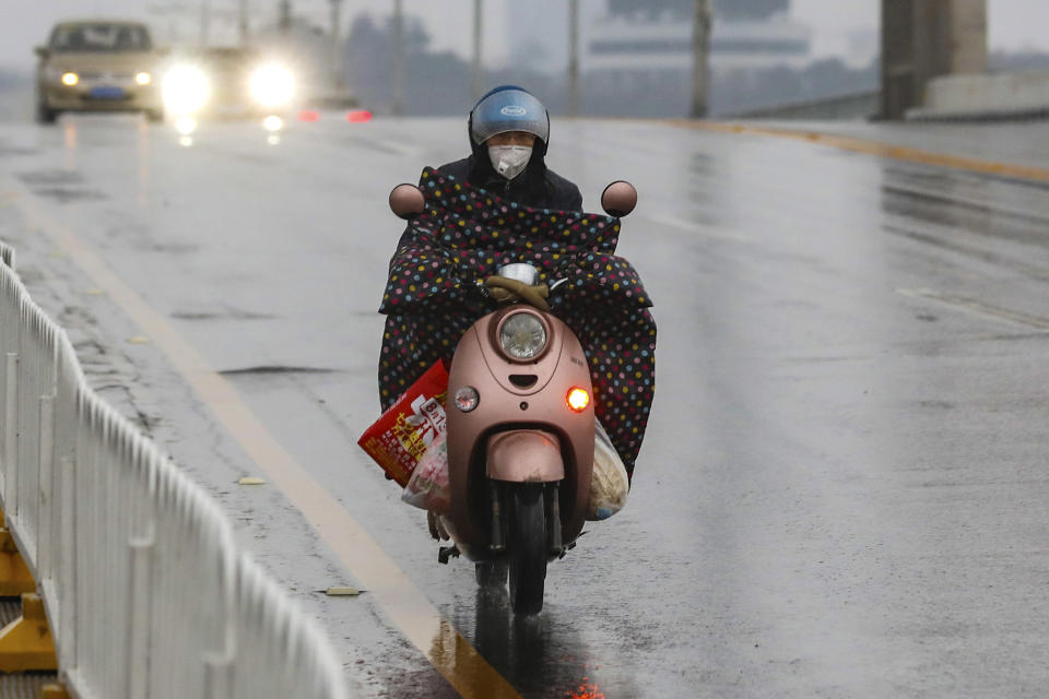 FILE - In this Saturday, Jan. 25, 2020, file photo, a motorcyclist wearing a face mask, rides across a bridge in Wuhan in central China's Hubei province. Face masks are in short supply in parts of the world as people try to stop the spread of a new virus from China. Health officials recommend strap-on medical masks for people being evaluated for the new virus, their household members and caregivers. (Chinatopix via AP, File)