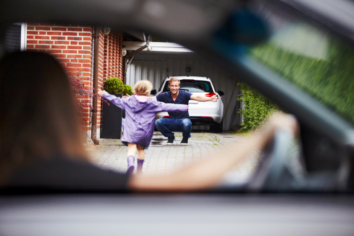 Cute little girl running towards her dad as her mom looks on from the car